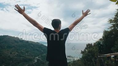 一位年轻的旅行者高高举起双手，<strong>站在山顶</strong>上